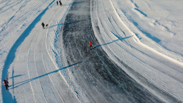 Aerial view of people ice skating and walking on a frozen lake in Luleå