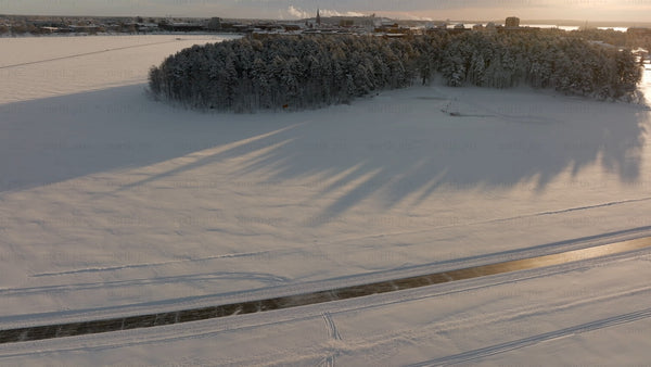Winter sunset over snowy Luleå: Aerial drone footage of frozen river and icy road