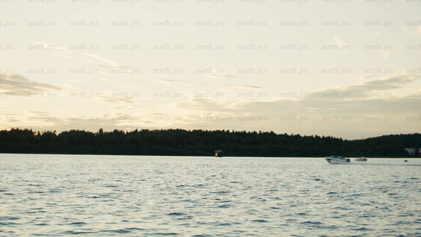 Sunset over the Luleå river: Motorboats sailing on a summer evening