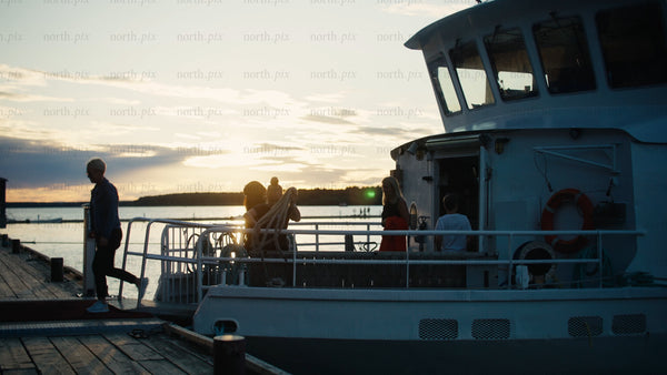 Friends and family disembark boat at sunset in Luleå