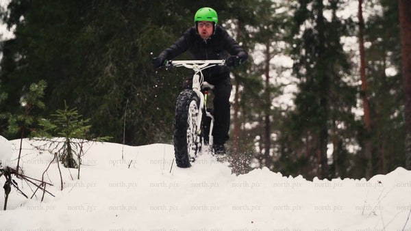 Man riding fatbike through snowy forest in Luleå, winter day