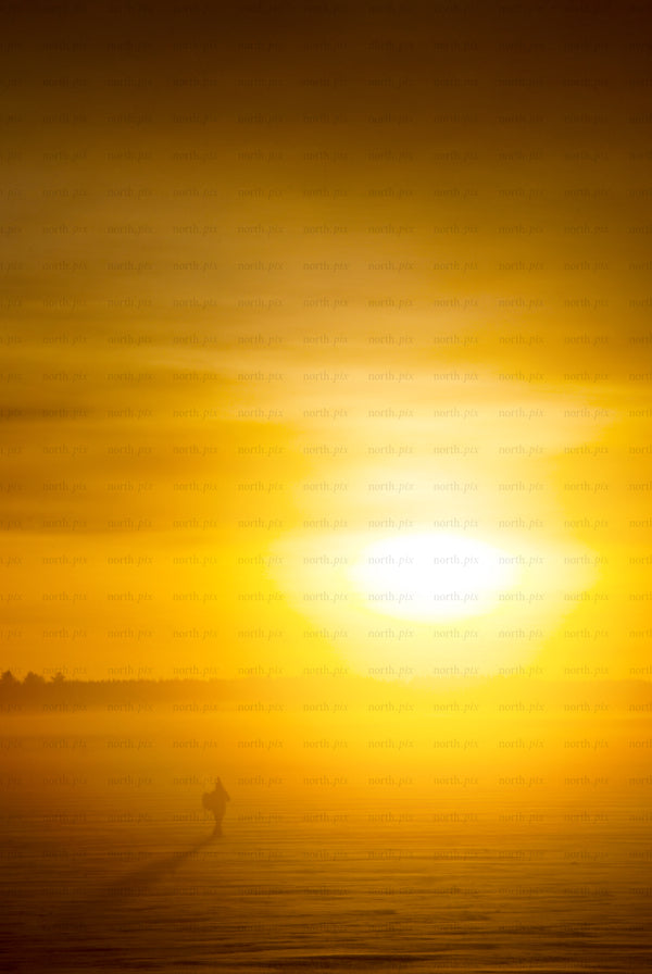 Man silhouette walking on frozen lake at sunrise
