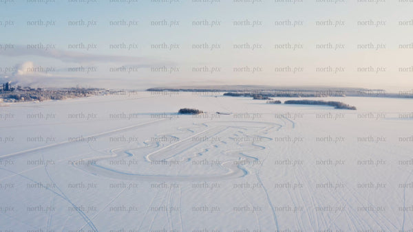 Aerial view of snowy Luleå landscape with snowmobile track on frozen lake in winter morning