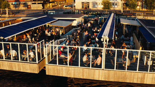 Aerial view of floating restaurant on Luleå river in summer evening with people enjoying drinks and food