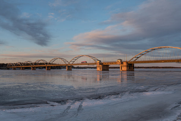 Arched bridge over frozen river at sunset