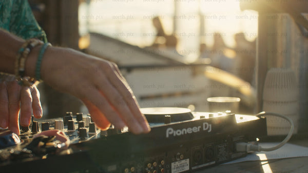 DJ mixing music on a pioneer controller at an urban summer event in Luleå during golden hour