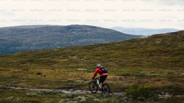 Man mountain biking down rocky terrain in scenic valley