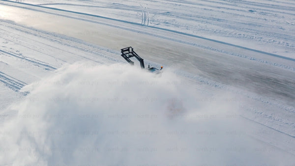 Snow blower clearing snowy road in winter, Luleå - aerial drone footage