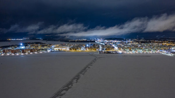 Luleå at night: Aerial drone timelapse of city center with fireworks over frozen lake in winter