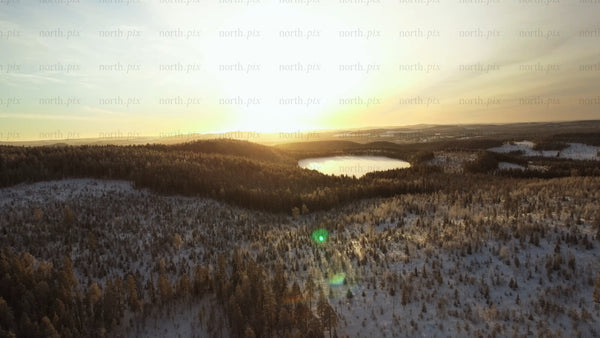 Winter sunset over frozen lake and snowy forest in Gunnarsbyn
