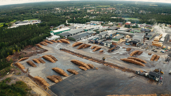 Aerial view of sawmill and lumber yard with stacks of logs in rural forest area