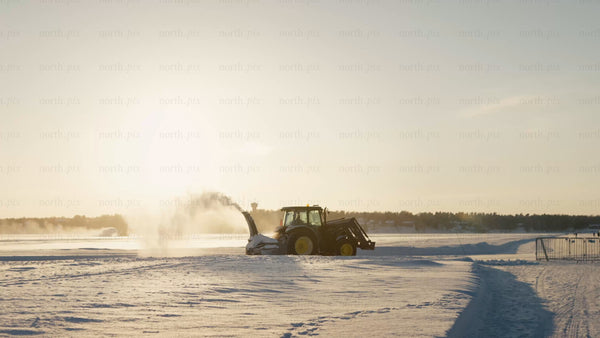 Tractor clearing snow on frozen lake in Luleå, on a bright winter day