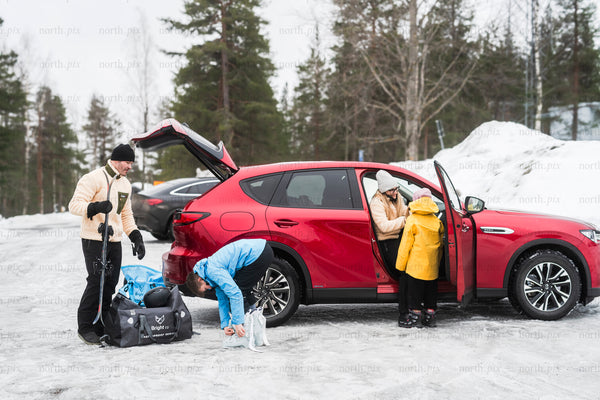 Family unloading car in snowy parking lot during winter day