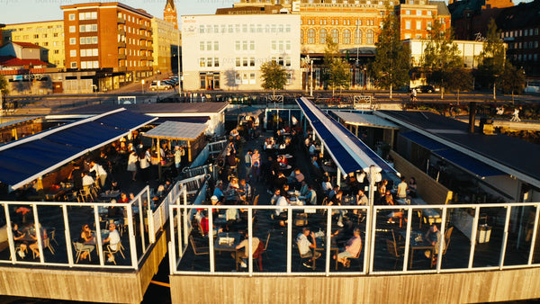 Summer evening at a waterfront bar in Luleå: Aerial view of people enjoying golden hour