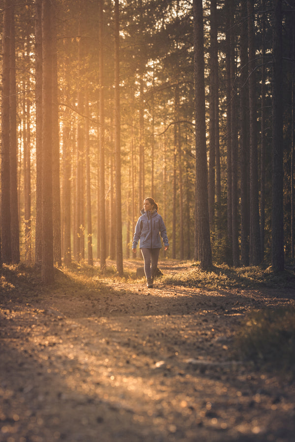 Woman walking on forest path at sunset