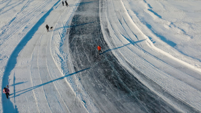 Aerial view of people ice skating and walking on a frozen lake in Luleå