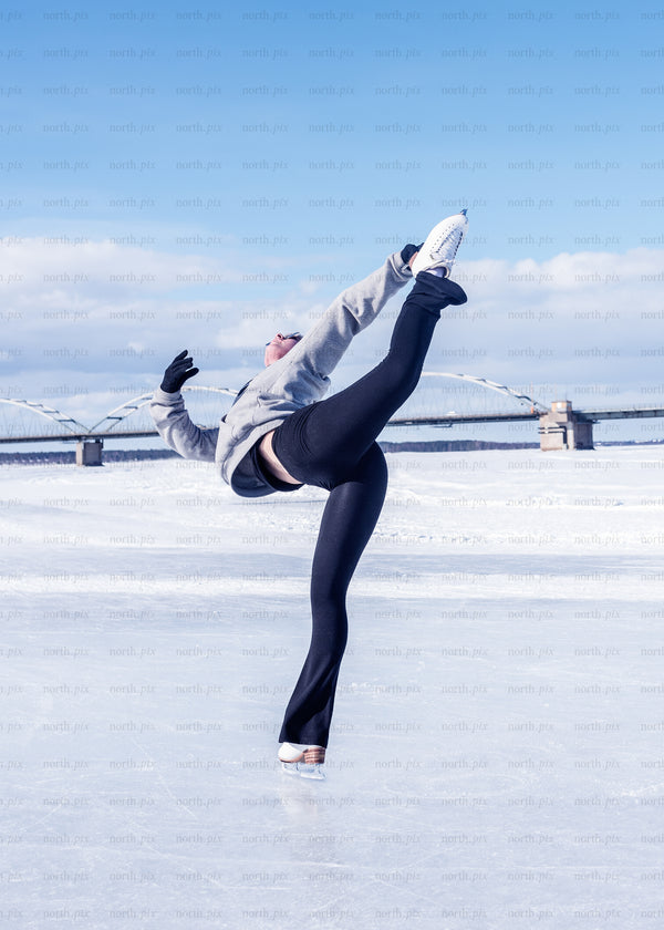 Skater on frozen river with bridge, winter daylight