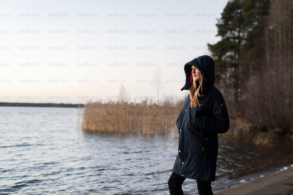 Woman standing on lake shore at dusk, autumn