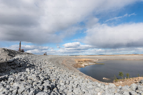 Rocky embankment and machinery by reservoir at midday