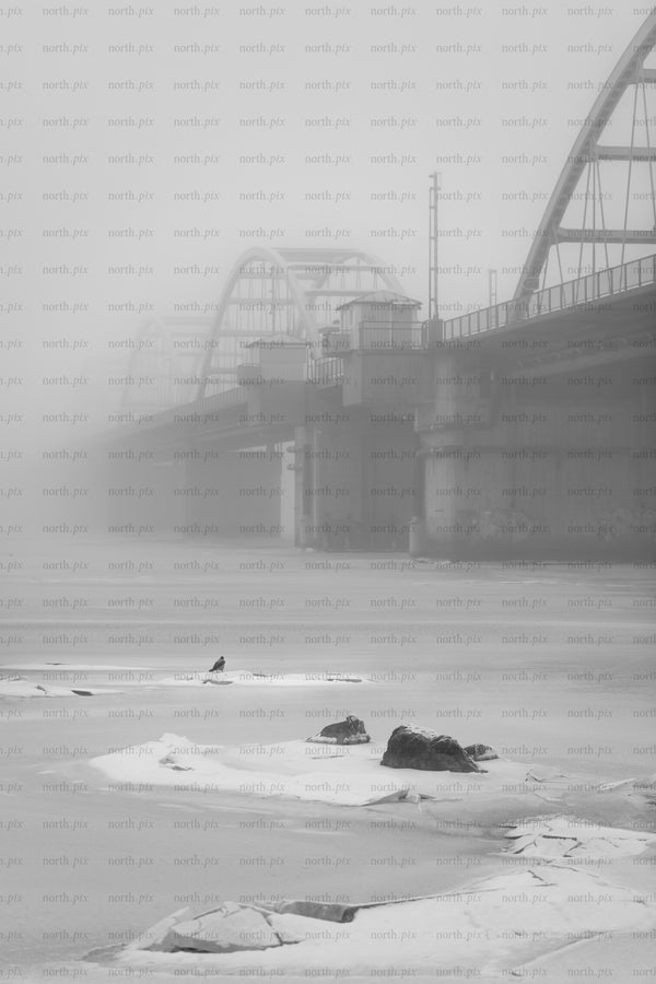 Bridge over frozen river in heavy fog