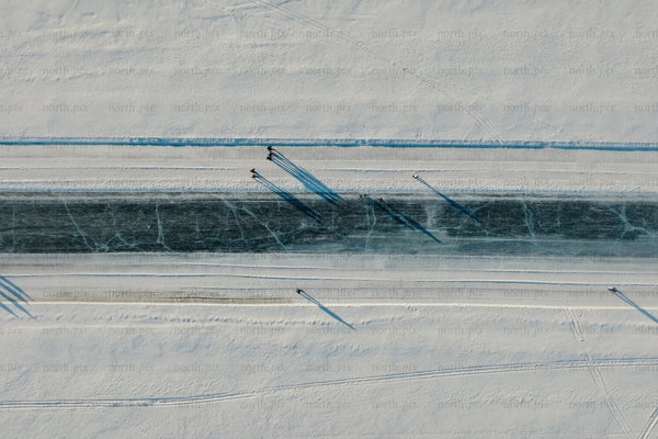 Aerial view of snowy canal in Luleå city center with skaters and long shadows