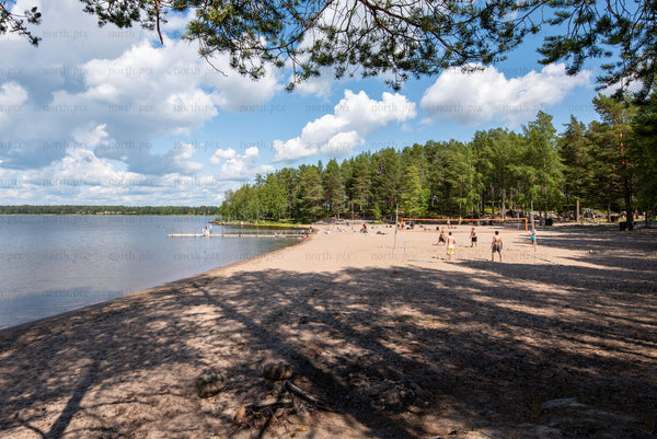 Sandy lakeside beach with volleyball courts, summer afternoon