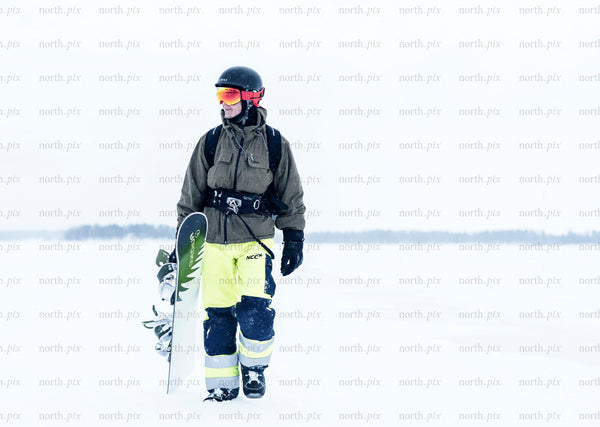 Snowboarder walking across snowfield in winter daytime