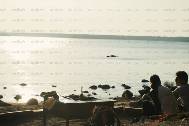 Relaxed lakeside evening with friends by the shore at sunset