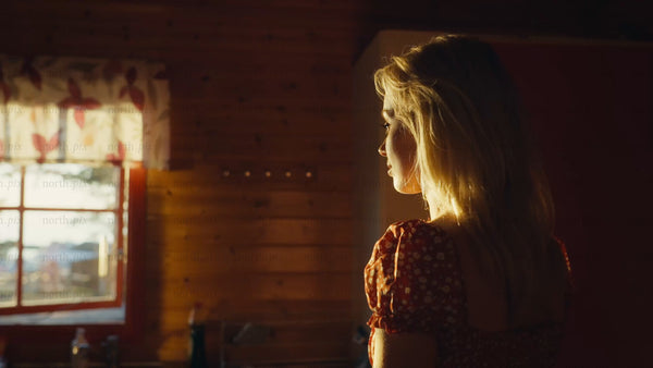 Woman gazing out cabin window during golden hour in Luleå