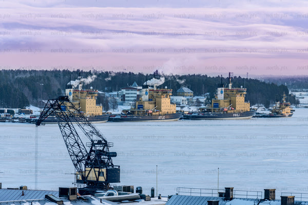 Icebreakers docked near crane at frozen harbor