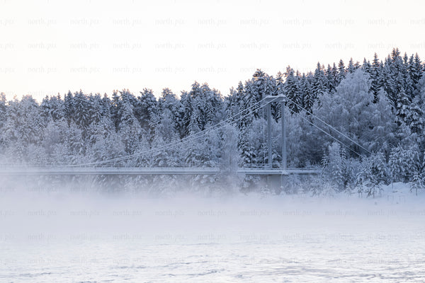 Suspension bridge crossing a river in snowy forest
