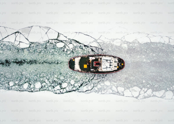 Icebreaker ship clearing frozen waters in wintertime overhead view
