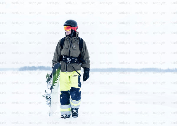Snowboarder walking across snowfield in winter daytime
