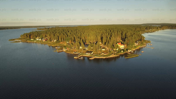 Aerial view of Piteå archipelago: Forested island with coastal houses and docks in Swedish waters
