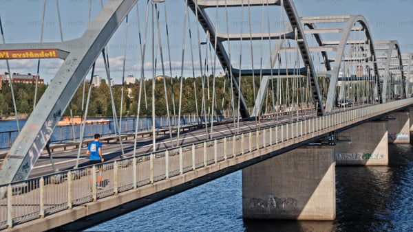 Runner crossing bridge in Luleå on a sunny summer day