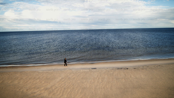 Woman walking on sandy beach by the sea in summer