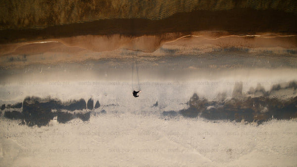 Winter beach walk: Aerial drone view of person in Skvalpen archipelago, Luleå
