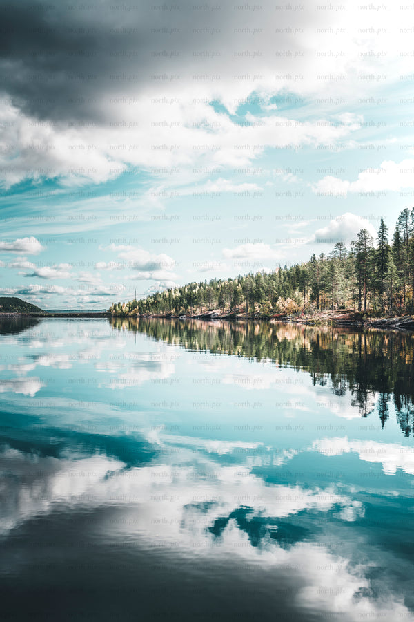 Lake with forested shoreline and sky reflection