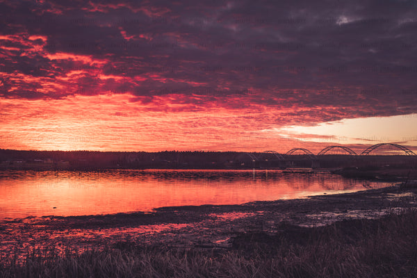 Arched bridge over river under red sunset sky