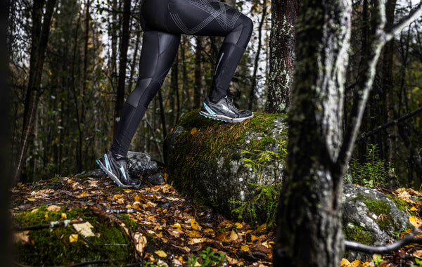 Runner stepping on mossy rock in autumn forest