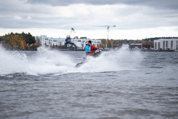 Person riding jet ski near harbor in autumn