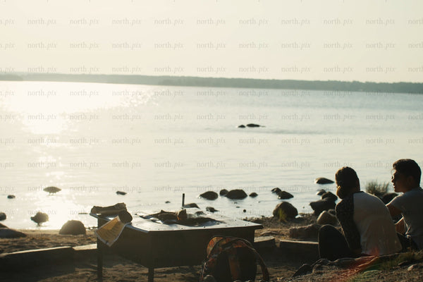 Relaxed lakeside evening with friends by the shore at sunset