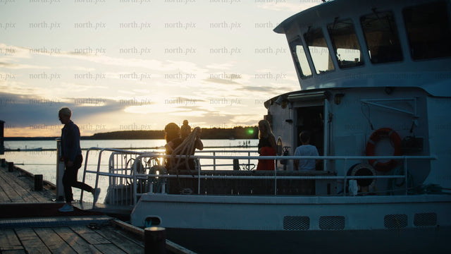 Friends and family disembark boat at sunset in Luleå