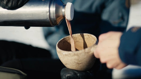 Pouring a hot drink into a kuksa mug in the winter Luleå archipelago