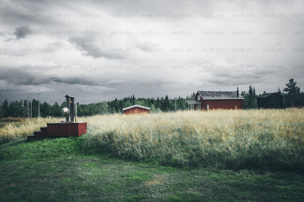 Rural field with wooden houses under cloudy sky