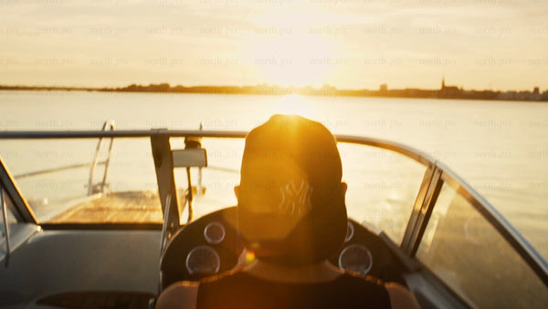 Man driving motorboat in Luleå archipelago at sunset during golden hour