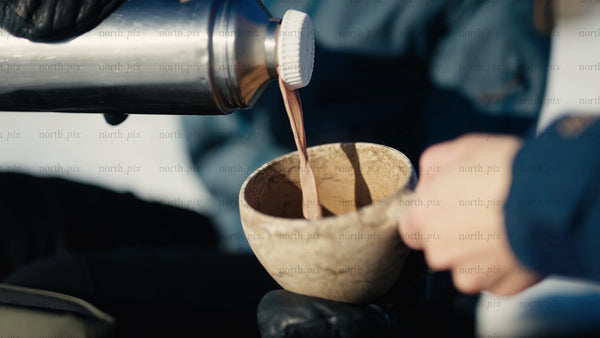 Pouring a hot drink into a kuksa mug in the winter Luleå archipelago