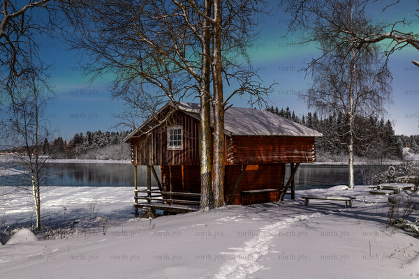 Red boathouse by a frozen lake at night, winter