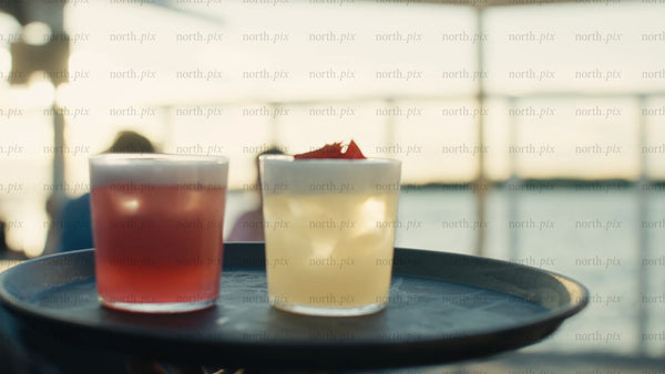 Waiter carries cocktails on a tray at an urban rooftop party during a summer evening
