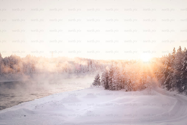 Sunrise over snowy river and forested bank